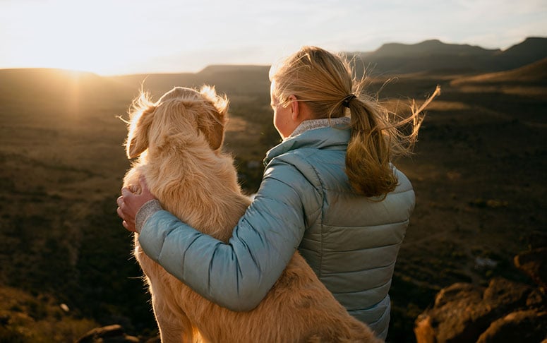 Woman with arm over dog outside