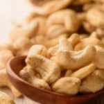 close up of cashew nuts in wood spoon on wood table