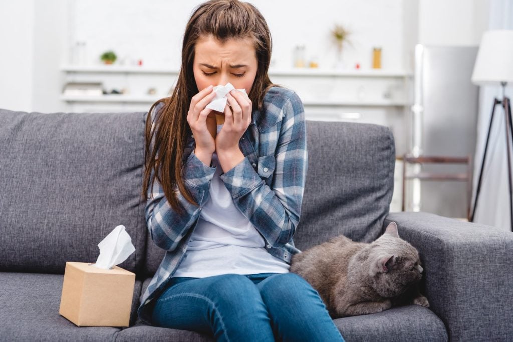 Woman sneezing with her cat 