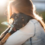 woman hugging black rescue dog