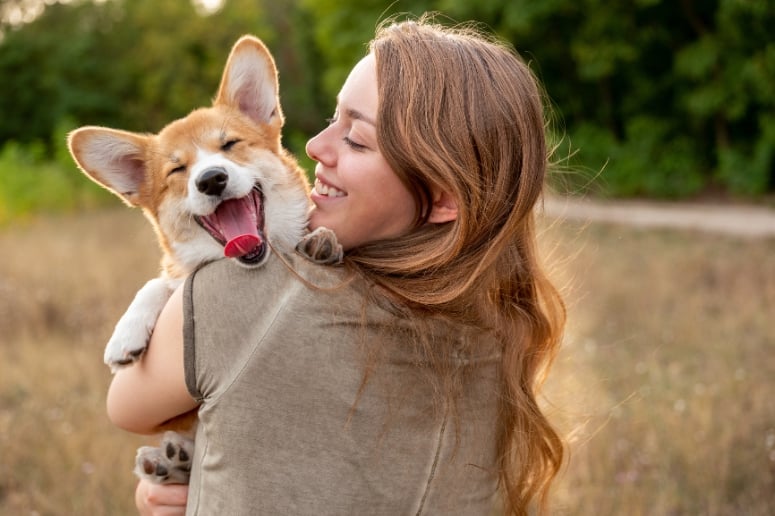 A happy Corgi held by a woman.