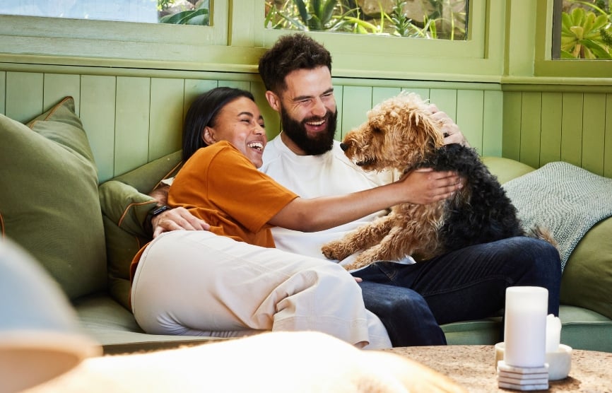 A couple cuddling with happy dog.