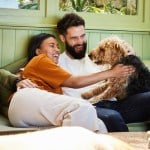 A couple cuddling with happy dog.